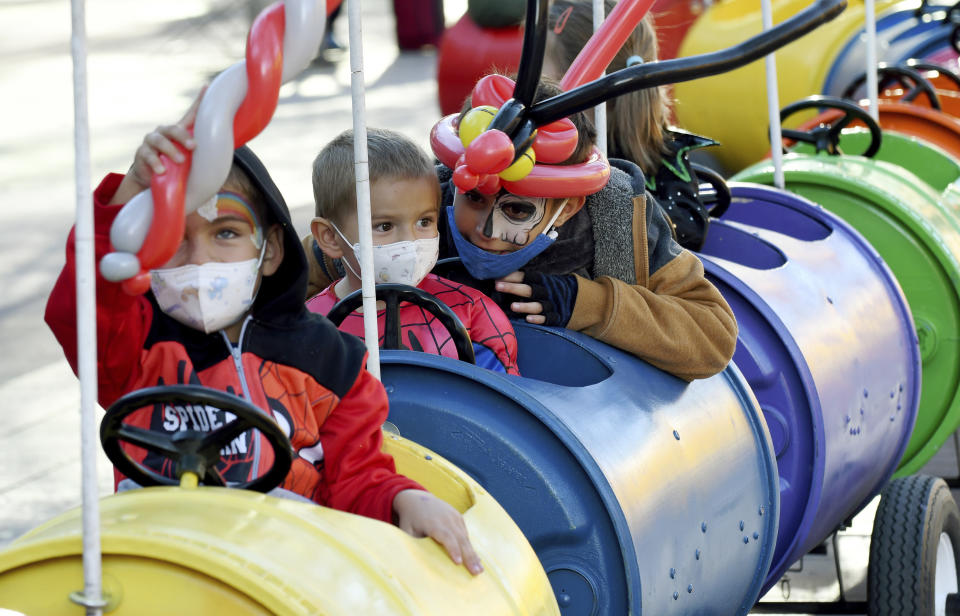 Max Moreno-Vishnevskiy, 3, center, rides a train during a Halloween celebration at Denver's Union Station on Thursday, Oct. 28, 2021. Though the pandemic remains a concern, top health officials are largely giving outside activities like trick-or-treating the thumbs up. (AP Photo/Thomas Peipert)