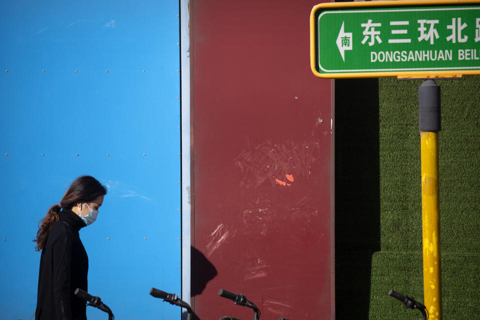 A woman wearing a face mask to protect against the coronavirus walks along a street in Beijing, Thursday, Oct. 22, 2020. The number of confirmed COVID-19 cases across the planet has surpassed 40 million, but experts say that is only the tip of the iceberg when it comes to the true impact of the pandemic that has upended life and work around the world. (AP Photo/Mark Schiefelbein)