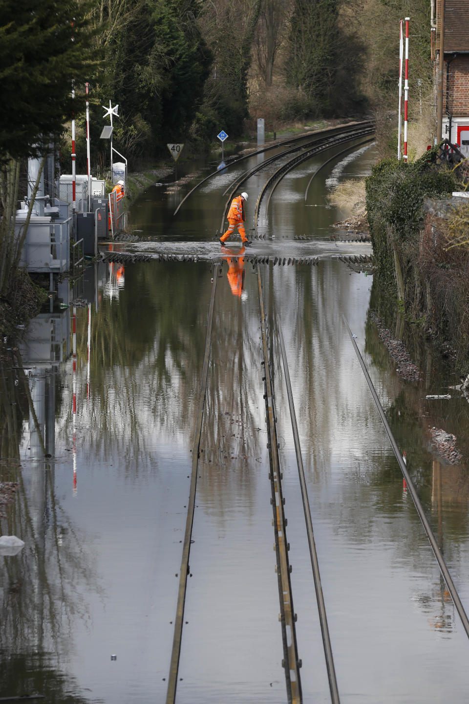 A railway workers walks across the flooded railway tracks, in Datchet, England, Monday, Feb. 10, 2014. The River Thames has burst its banks after reaching its highest level in years, flooding riverside towns upstream of London. Residents and British troops had piled up sandbags in a bid to protect properties from the latest bout of flooding to hit Britain. But the floods overwhelmed their defences Monday, leaving areas including the centre of the village of Datchet underwater. (AP Photo/Sang Tan)