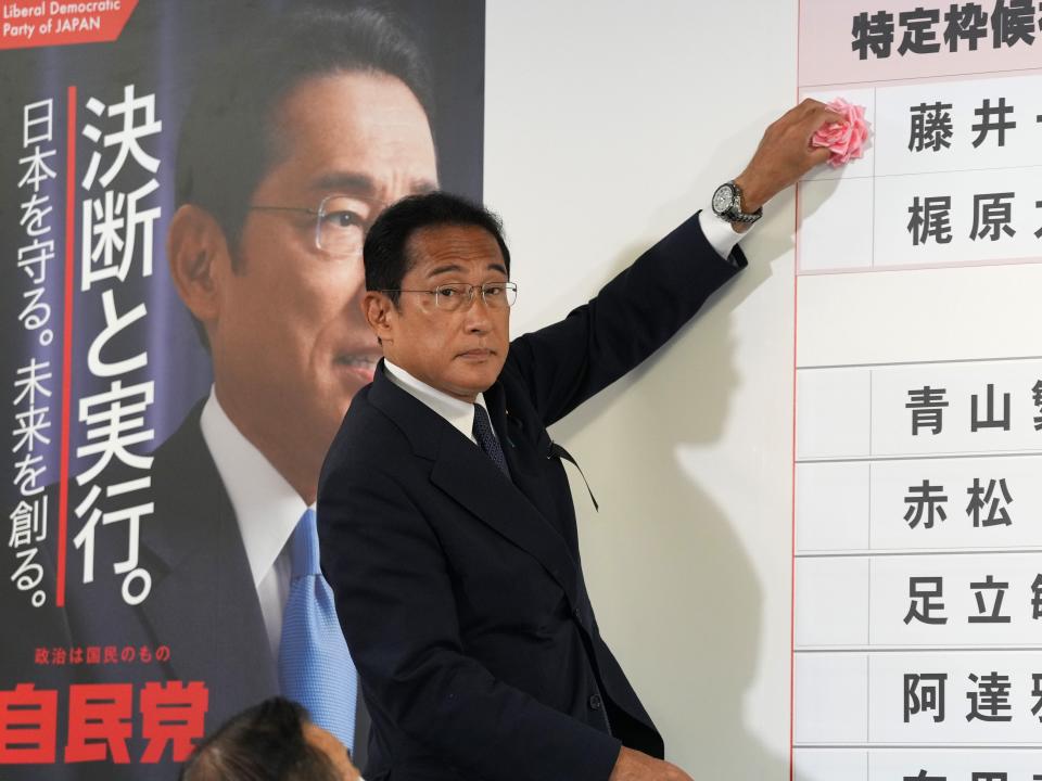 Fumio Kishida, Japan's prime minister and president of the Liberal Democratic Party (LDP), places a rose on an LDP candidate's name, to indicate a victory in the upper house election, at the party's headquarters in Tokyo, Japan, on Sunday, July 10, 2022.