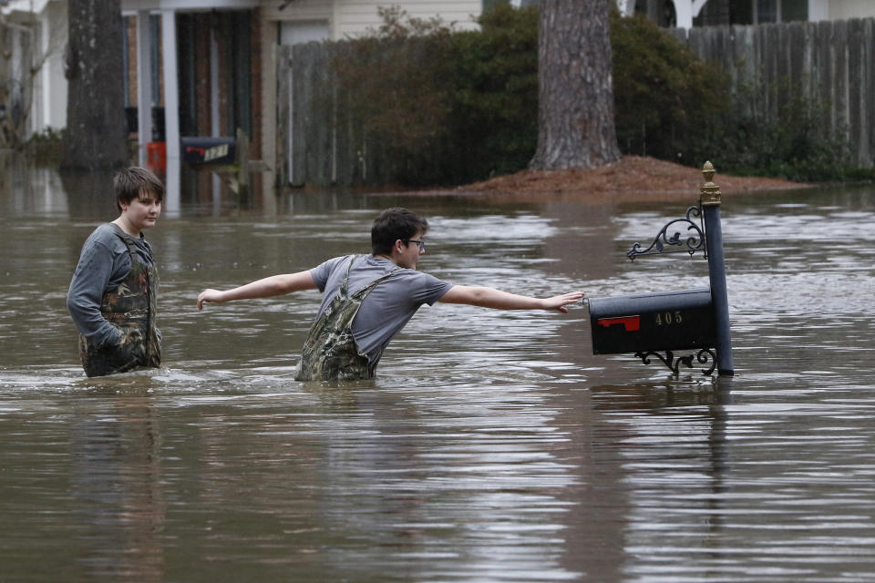 Blaine Henderson, right, reaches to tag a mailbox as Pearl River as he and his friend Jonah Valdez, both 12, play in the floodwaters of this northeast Jackson, Miss., neighborhood, Sunday, Feb. 16, 2020. (AP Photo/Rogelio V. Solis)