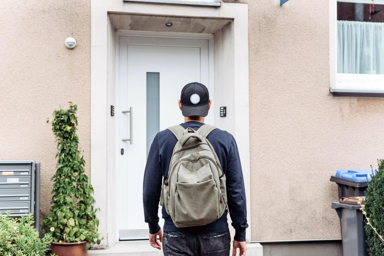 man with backpack looking at apartment he is about to enter