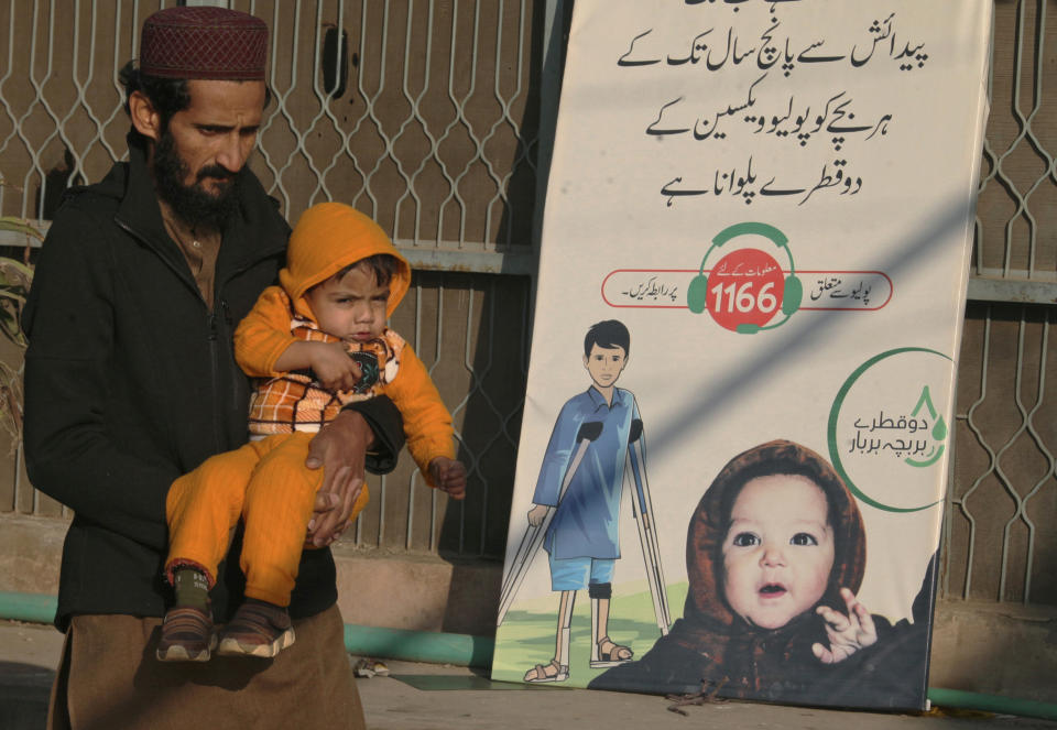 A man with a child leaves after polio vaccination of his child at a health center, in Peshawar, Pakistan, Monday, Jan. 24, 2022. Pakistani authorities launched the year's first anti-polio campaign even as coronavirus cases suddenly rise in an effort to eradicate the crippling children's disease. (AP Photo/Muhammad Sajjad)