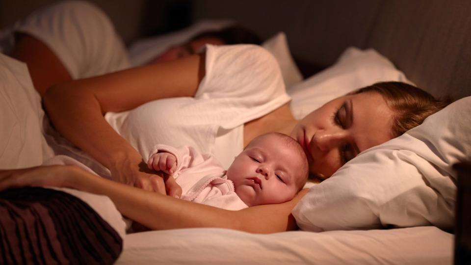 Parents Sleeping In Bed With Newborn Baby