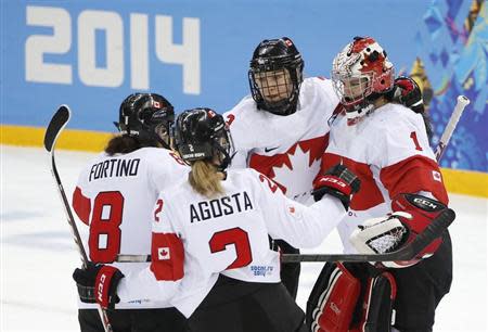 Canada's goalie Shannon Szabados (R) is congratulated by teammates Jocelyne Larocque (C), Laura Fortino (8) and Meghan Agosta-Marciano (2) after they defeated Switzerland in their women's ice hockey semi-final game at the Sochi 2014 Winter Olympic Games February 17, 2014. REUTERS/Jim Young