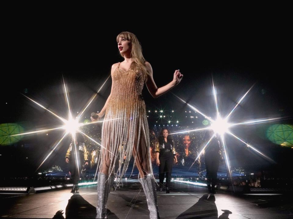 Taylor Swift performs in a gold and silver dress.