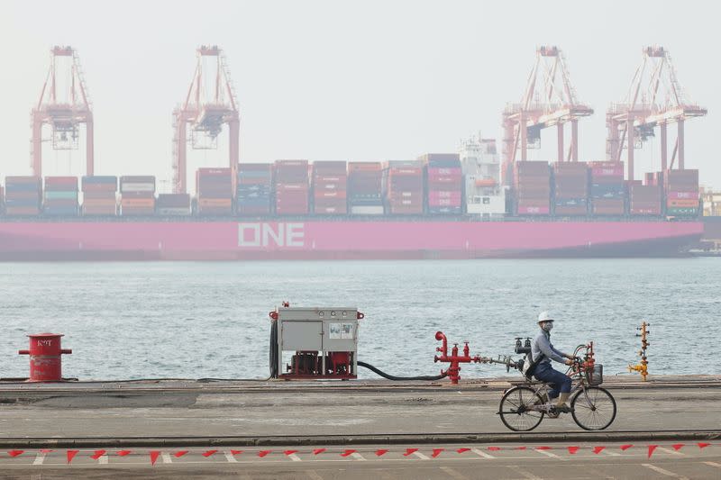 A member of staff riding a bike passes the site of the ceremony for the start of construction of a new submarine fleet in Kaohsiung