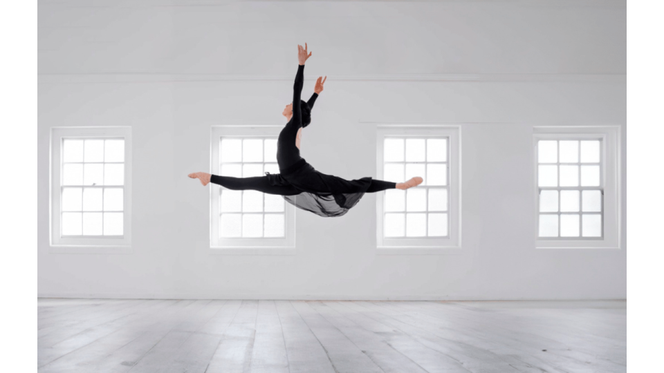 ballerina jumping in the air in a white studio 