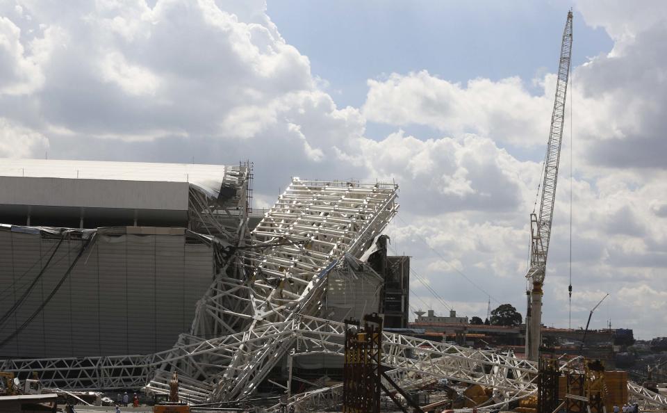 Workers stand next to a crane that collapsed on the site of the Arena Sao Paulo stadium, known as "Itaquerao", which will host the opening soccer match of the 2014 World Cup, in Sao Paulo