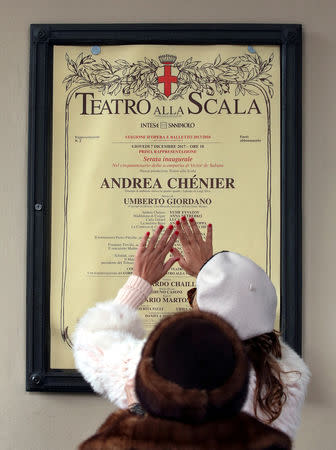 FILE PHOTO: A woman gestures in front of the programme of "Andrea Chenier" outside La Scala opera house in Milan, Italy, December 7, 2017. REUTERS/Stefano Rellandini/File Photo