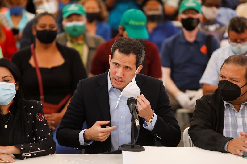 Venezuelan opposition leader Juan Guaido removes his face mask while arriving to a news conference in Caracas