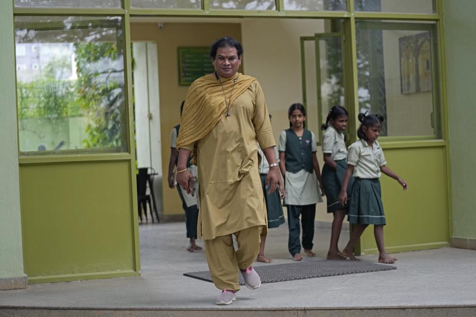 Preethi, a 38-year-old transgender woman who uses only her first name, walks out with students of Shishu Mandir, an organization which provided her an electric auto rickshaw to earn her livelihood, in Bengaluru, India, Monday, July 10, 2023. She's now one of millions of electric vehicle owners in India, but one of very few to have received an EV through a charitable donation. (AP Photo/Aijaz Rahi)