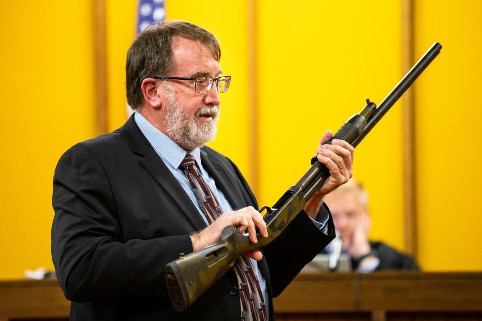 Michael Tate, a state firearm technician, holds a shotgun as he testifies during the trial of Michael Lang at the Hamilton County Courthouse on Thursday.