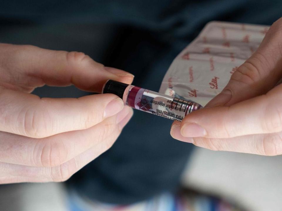  A diabetes patient holds a vial of insulin.