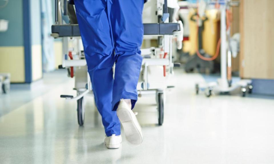 Hospital worker pushing a stretcher down a corridor