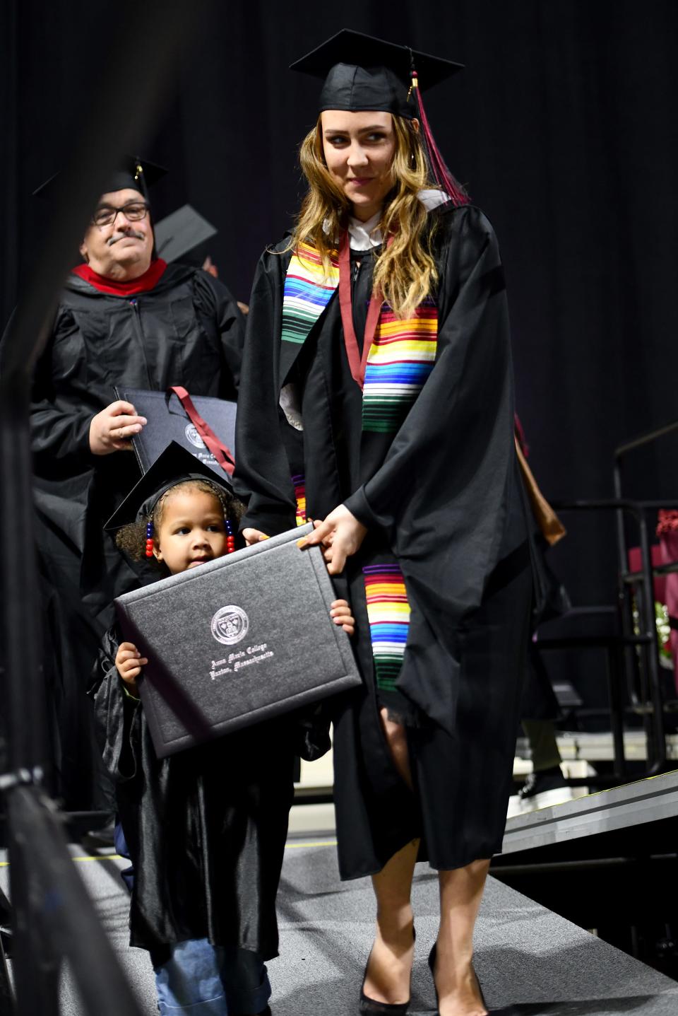 Mariah Vega of Worcester allows her daughter, Aliana Vega-Walker, 3, to help carry her master of arts in counseling psychology diploma during Anna Maria College's 74th commencement exercises at the DCU Center Monday.