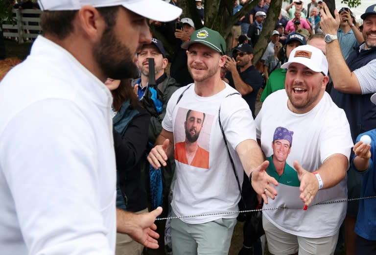 Top-ranked Scottie Scheffler shakes hands with fans, one wearing a T-shirt bearing the image of his mugshot from jail, during the second round of the PGA Championship (Patrick Smith)