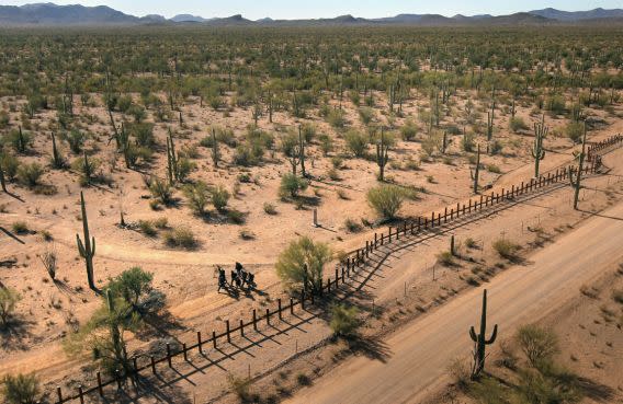 Personas caminan del lado mexicano de la frontera entre México y EEUU, marcada con una valla de estacas. Del otro lado es el territorio de la reservación Tohono O'odham en Arizona. (Getty Images)