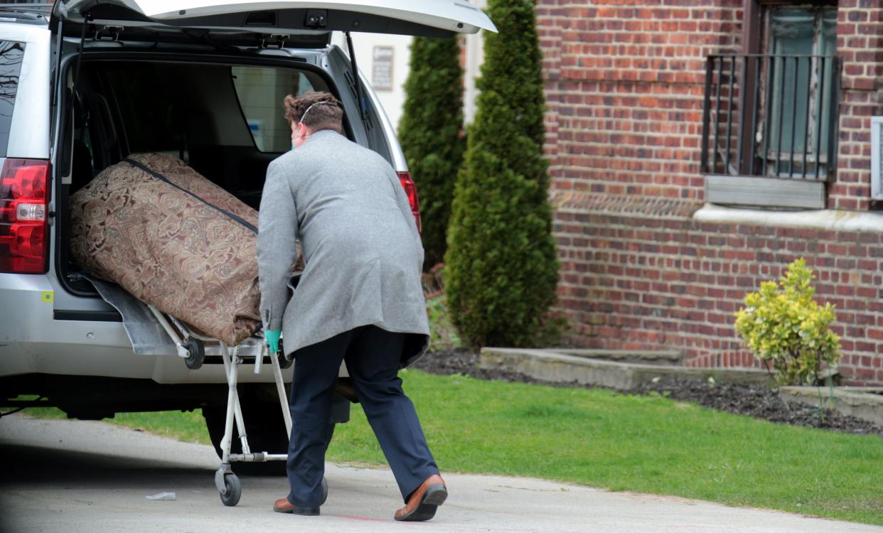 FILE - A funeral home worker is seen removing a body from the Flushing Hospital in Queens on April 20, 2020, during the coronavirus pandemic outbreak. 
