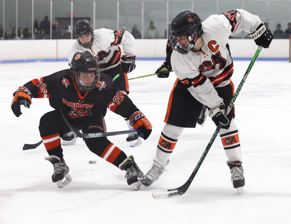 Oliver Ames Elliiot Cohen passes the puck between his legs to Jack Corey in front of Taunton's Travis Cashman during a game on Saturday, Jan. 8, 2022.  