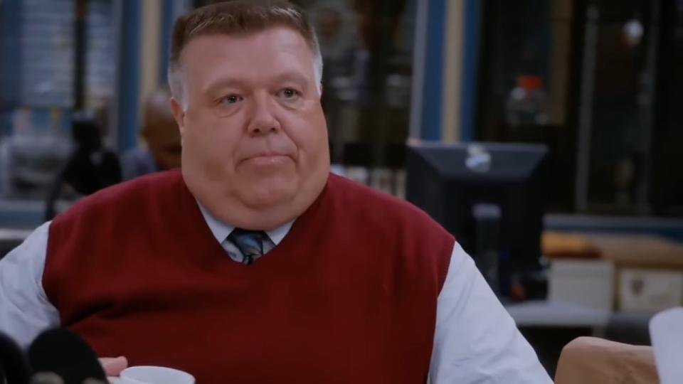Scully sitting at his desk in a red sweater vest in "Brooklyn Nine-Nine"