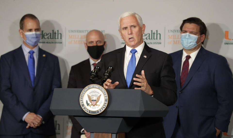 Vice President Mike Pence, second from left, speaks during a news conference as Rep. Mario Diaz-Balart, R-Fla., left, Food and Drug Administration Commissioner Dr. Stephen Hahn, second from left, and Florida Gov. Ron DeSantis, right, look on at the University of Miami Miller School of Medicine Don Soffer Clinical Research Center, Monday, July 27, 2020, in Miami. Pence was in Florida to mark the beginning of Phase III trials for a coronavirus vaccine. (AP Photo/Wilfredo Lee)