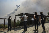 A plane pours water over the fire-devastating Sirtkoy village, near Manavgat, Antalya, Turkey, Sunday, Aug. 1, 2021. More than 100 wildfires have been brought under control in Turkey, according to officials. The forestry minister tweeted that five fires are continuing in the tourist destinations of Antalya and Mugla. (AP Photo)