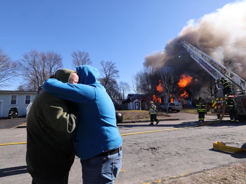 Resident Mandy Adao, left, weeps as she is comforted as firefighters from multiple communities battle a two-alarm fire at her house at 53 Old Bedford Road in East Bridgewater on Sunday, Feb. 4, 2024.