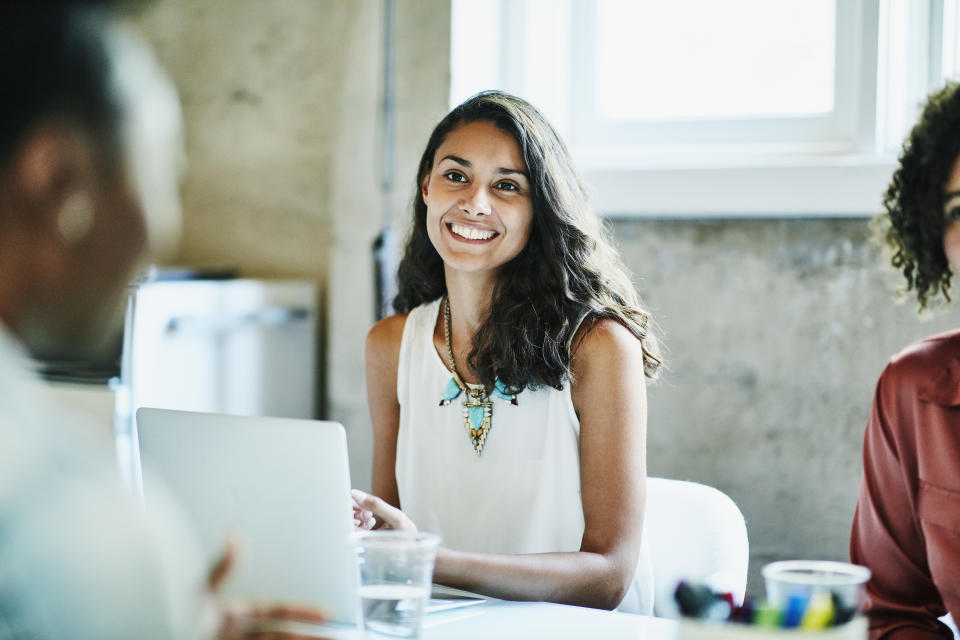 Smiling businesswoman in discussion with colleagues during meeting in office conference room