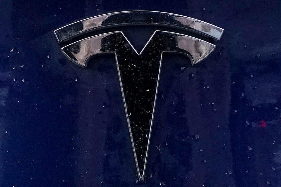 FILE - A Tesla electric vehicle emblem is affixed to a passenger vehicle Sunday, Feb. 21, 2021, in Boston. Tesla is dropping prices for the third time since late last year in an apparent effort to attract new buyers. The cuts range from $5,000 for slower-selling high-priced models to $1,000 at the low end of its price range. (AP Photo/Steven Senne, File)