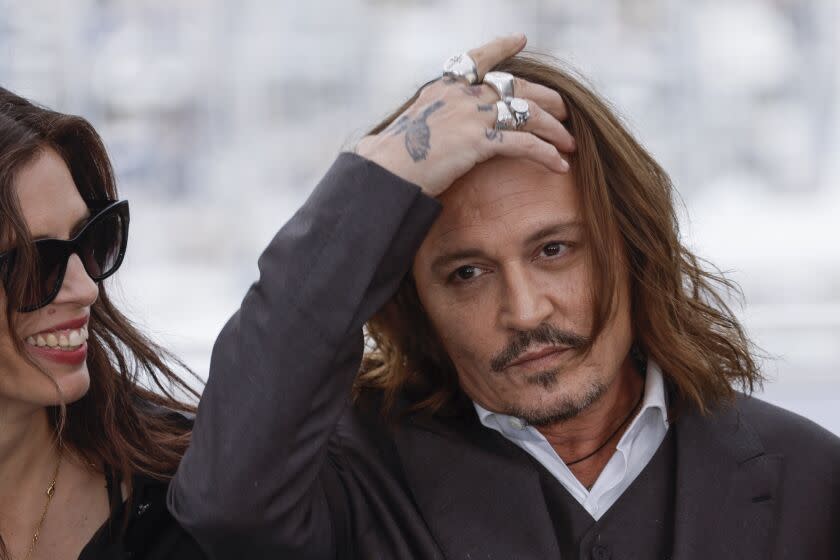 Johnny Depp holds his hand above his forehead as a woman smiles next to him