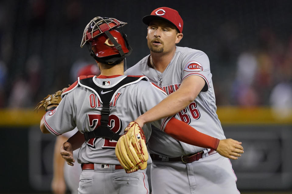 Cincinnati Reds' catcher Chris Okey, left, embraces relief pitcher Joel Kuhnel after the 12th inning of a baseball game against the Arizona Diamondbacks', Tuesday, June 14, 2022, in Phoenix. The Reds defeated the Diamondbacks 5-3. (AP Photo/Matt York)