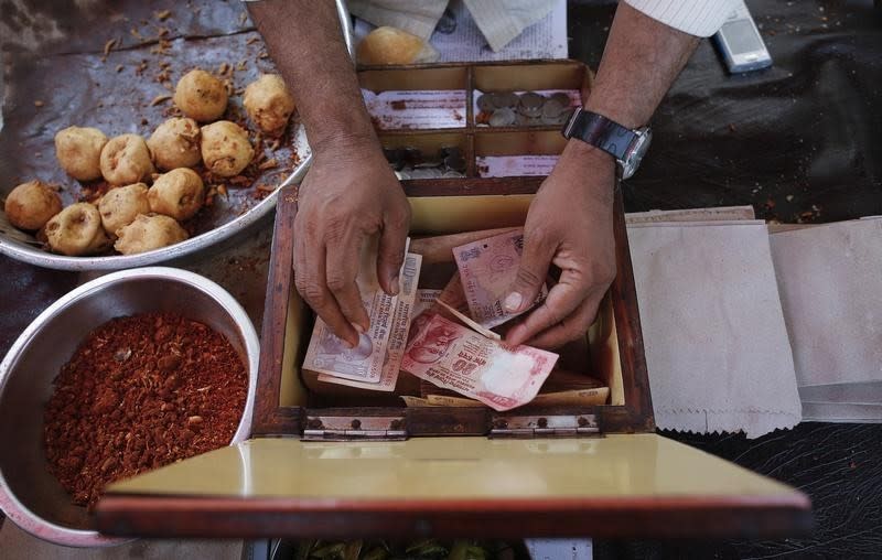 A streetside restaurant owner keeps money received from a customer in Mumbai December 5, 2013. REUTERS/Danish Siddiqui/Files