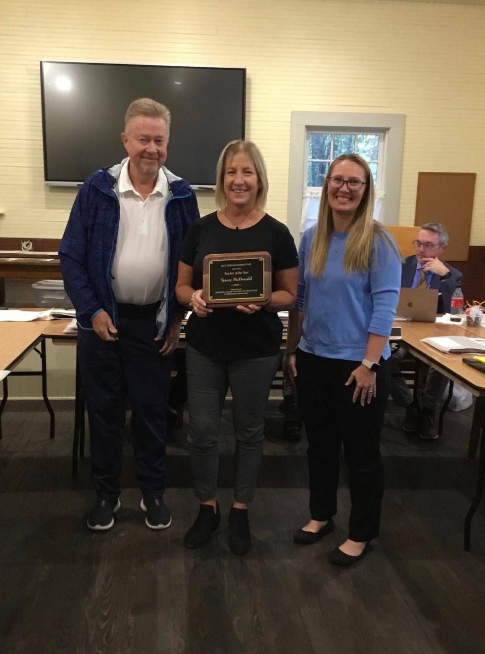 Tracey McDonald holds a plaque commemorating her as Hot Springs Elementary's 2023 Teacher of the Year while posing with Madison County Board of Education member Keith Ray and Hot Springs Elementary Principal Jennifer Mills.