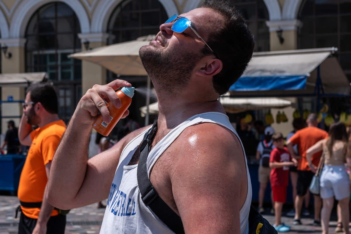 A man sprays sunscren on himself at Monastiraki square in Athens on July 12, as sweltering temperatures hit Greece (AFP via Getty Images)