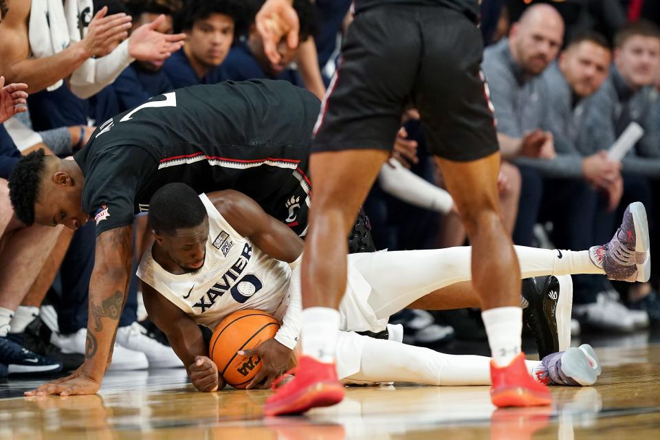 Xavier Musketeers guard Souley Boum (0) and Cincinnati Bearcats guard Landers Nolley II (2) compete for a loose ball in the first half of the 90th Crosstown Shootout college basketball game, Saturday, Dec. 10, 2022, at Fifth Third Arena in Cincinnati. 