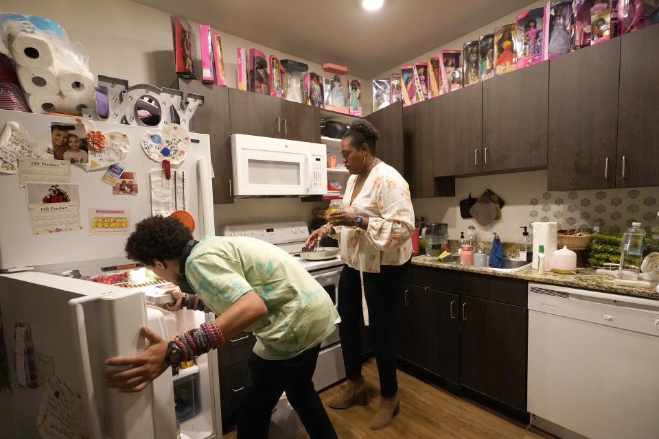 Miles Fallon, left, and his mother, Marla Williams, work in the kitchen as she prepares dinner at their home in Chicago, Wednesday, Oct. 12, 2022. During remote learning, Williams says Miles lost motivation and wouldn’t do his assignments. Once he went back on a hybrid schedule in spring 2021, he started doing well again, she says. (AP Photo/Charles Rex Arbogast)