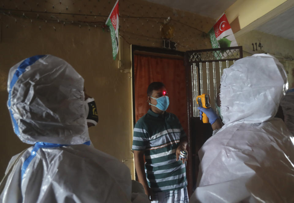Health workers screen people for COVID-19 symptoms at a residential building in Dharavi , one of Asia's biggest slums, in Mumbai, India, Friday, Aug. 7, 2020. As India hit another grim milestone in the coronavirus pandemic on Friday, crossing 2 million cases and more than 41,000 deaths, community health volunteers went on strike complaining they were ill-equipped to respond to the wave of infection in rural areas. (AP Photo/Rafiq Maqbool)