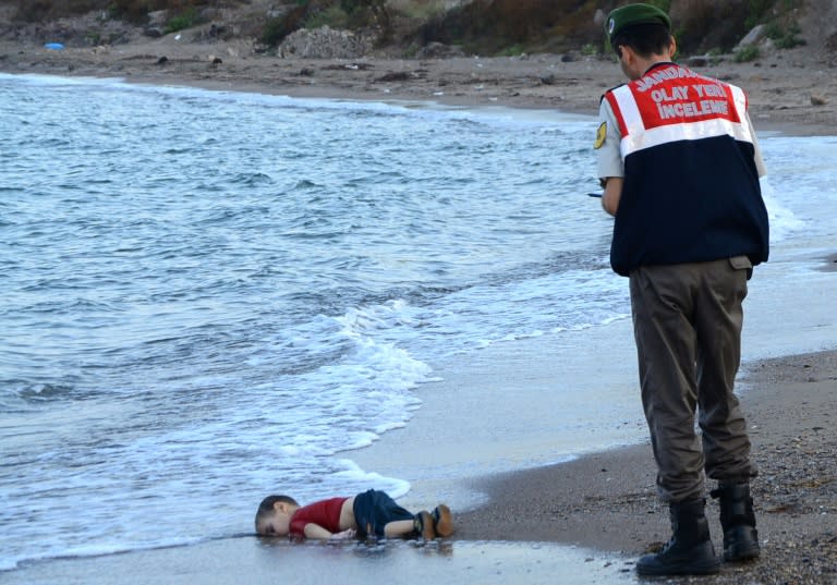 A Turkish police officer stands next to the body of Aylan Kurdi in September 2015