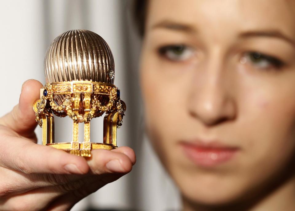 An assistant poses for a photograph with a Faberge egg during a photo-call at antique dealer Wartski, in central London