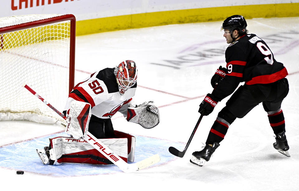 New Jersey Devils goaltender Nico Daws (50) makes a save on Ottawa Senators center Josh Norris (9) during the third period of an NHL hockey game, Friday, Dec. 29, 2023 in Ottawa, Ontario. (Justin Tang/The Canadian Press via AP)