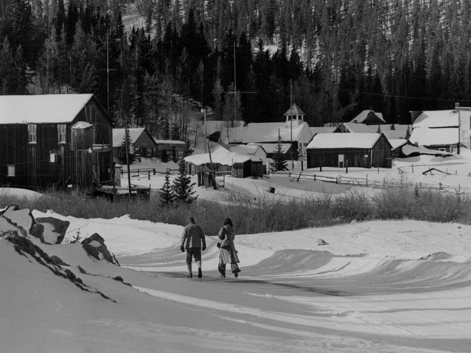 black and white photo of st elmo colorado and two people walking through the snow