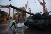 A harbour worker pushes a barrier next to the South Korean Black Panther K2 tank in the Polish Navy port of Gdynia, Poland, Tuesday, Dec. 6, 2022. Poland's President Andrzej Duda and the defense minister on Tuesday welcomed the first delivery of tanks and howitzers from South Korea, hailing the swift implementation of a deal signed in the summer in the face of the war in neighbouring Ukraine. (AP Photo/Michal Dyjuk)