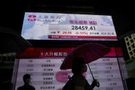 People wearing face masks walk past a bank's electronic board showing the Hong Kong share index in Hong Kong, Tuesday, June 22, 2021. Asian shares have rebounded from their retreat a day earlier, tracking Wall Street's recovery from the Federal Reserve's reminder it will eventually provide less support to markets. (AP Photo/Kin Cheung)