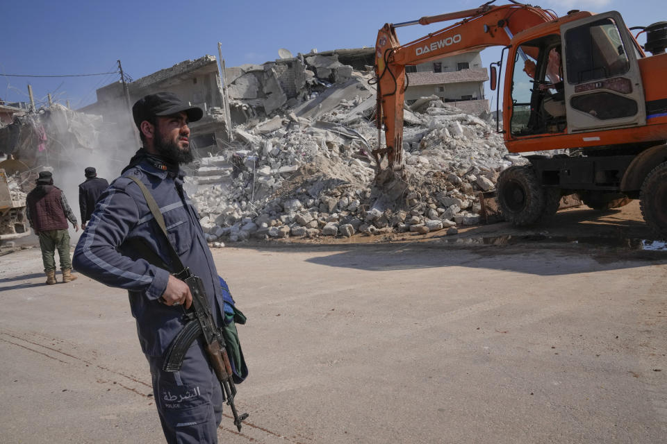 A militant of the al-Qaida-linked Hayat Tahrir al-Sham organisation stands in front of a destroyed house in Atareb, Syria, Sunday, Feb. 12, 2023. Six days after a massive earthquake killed thousands in Syria and Turkey, sorrow and disbelief are turning to anger and tension over a sense that there has been an ineffective, unfair and disproportionate response to the historic disaster. (AP Photo/Hussein Malla)