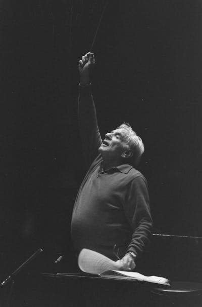 A man at a lectern with raised hand.