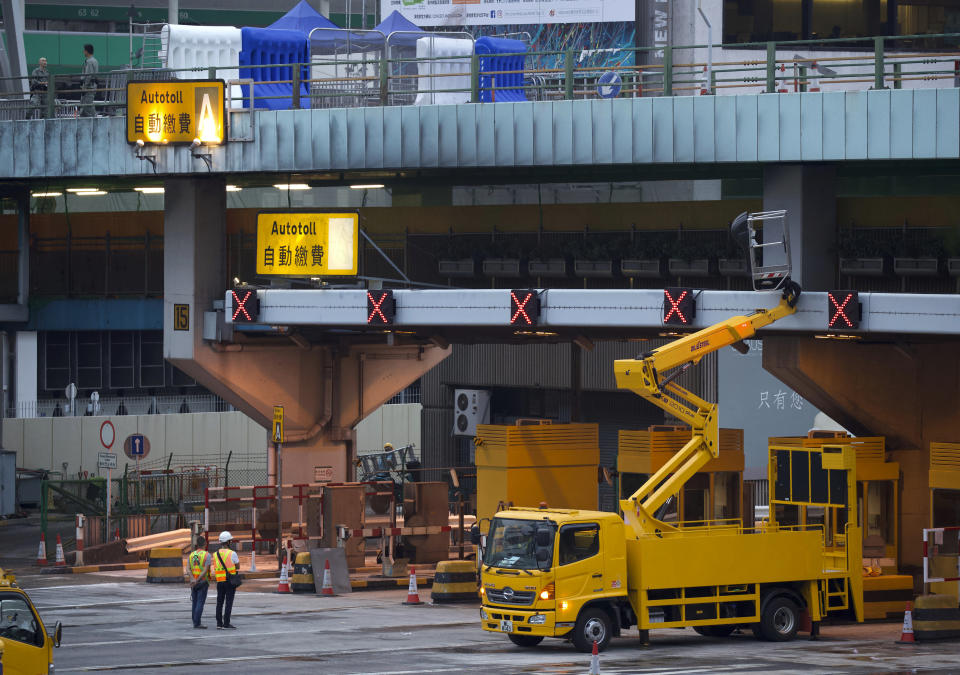 Workers repair tollbooths for the Cross-Harbour Tunnel near the Hong Kong Polytechnic University in Hong Kong, Tuesday, Nov. 26, 2019. A weeklong police siege of a university in Hong Kong may be winding down, closing one of the more violent chapters in the city's long-running anti-government protests. (AP Photo/Ng Han Guan)