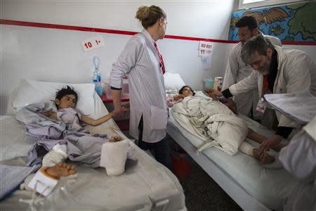 Nurse Nicole Burwood (2nd L) holds the hand of Gullali, 10, who sustained bullets injuries, during a follow-up visit of patients at Emergency hospital in Kabul March 27, 2014. REUTERS/Zohra Bensemra