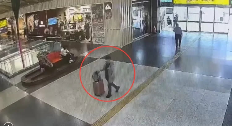張嫌推著行李相與寵物袋進入板橋車站大廳準備搭高鐵逃亡。翻攝畫面