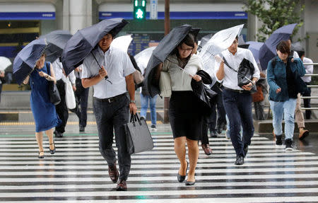 Passersby using umbrellas struggle against a heavy rain and wind as Typhoon Shanshan approaches Japan's mainland in Tokyo, Japan August 8, 2018. REUTERS/Toru Hanai